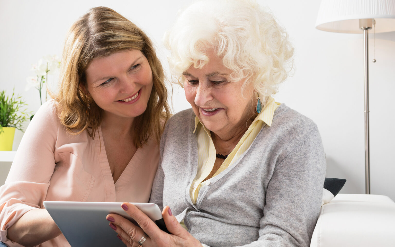 A middle-aged daughter and her mother read her life story on an eBook on an iPad.