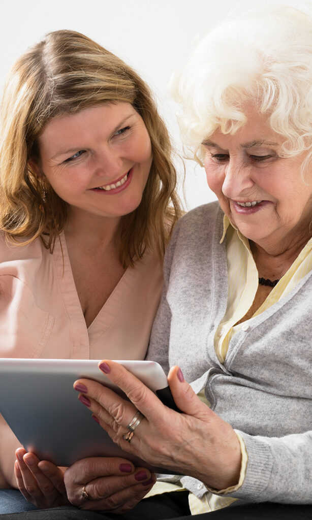 A middle-aged daughter and her mother read her life story on an eBook on an iPad.